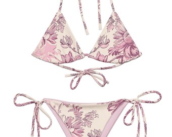 May include: A two-piece bikini set with a floral pattern in shades of pink and cream. The top is a halter style with tie closures, and the bottoms are a classic cut with side ties. The fabric features a repeating floral design.