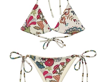 May include: A two-piece bikini set with a floral pattern. The top is a triangle style with tie straps, and the bottom is a string bikini. The fabric is off-white with a colorful floral design in red, green, and blue.