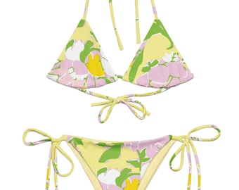 May include: A two-piece bikini set with a floral pattern. The top is a halter style with triangle cups, and the bottom is a tie-side style. The floral pattern features yellow, pink, green, and white colors. The bikini is made of a soft, lightweight material.
