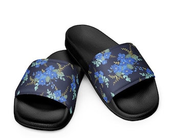 May include: Black slide sandals with a navy blue floral pattern featuring blue flowers and green leaves. The sandals have a black sole and a floral design across the top.