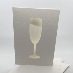 May include: A stack of blank white cards with a single card featuring a cut-out silhouette of a champagne flute.