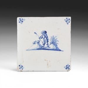 May include: Square white ceramic tile with a blue and white illustration of a person fishing. The figure is dressed in period clothing and stands on a small hill. Floral corner accents complete the design.