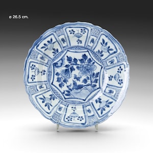 Op de afbeelding: Een blauw-wit keramisch bord met een bloemen- en vogelontwerp. Het bord heeft een geschulpte rand en meet 26,5 cm in diameter.