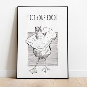 May include: Black and white illustration of a bird wearing a slice of bread as a hat. The text "HIDE YOUR FOOD!" is above the bird. The artwork is framed in a black frame.