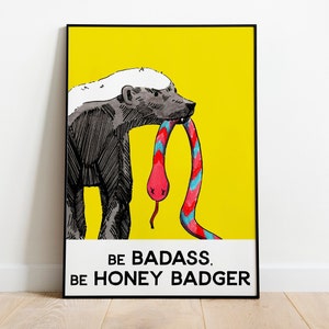 May include: A yellow poster with a black border featuring a cartoon honey badger with a white stripe on its head. The honey badger is biting a pink and blue snake. The text on the poster reads "Be badass. Be honey badger."