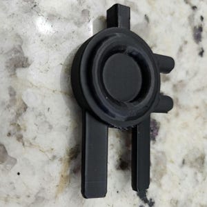 May include: A black 3D printed object with a circular design and two long, thin arms. The object is made of plastic and has a smooth, matte finish.