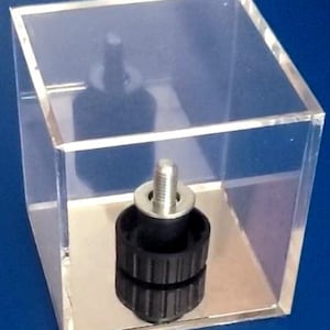 May include: A black and silver screw-on furniture leg with a threaded metal shaft and a black rubber base, displayed in a clear acrylic cube.