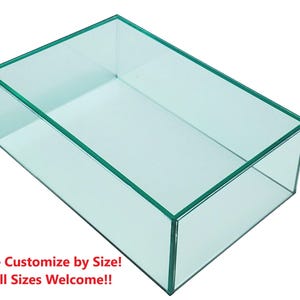 May include: A rectangular glass display case with a clear, transparent design. The edges are outlined with a subtle green tint. Text at the bottom reads: "We Customize by Size! All Sizes Welcome!!"