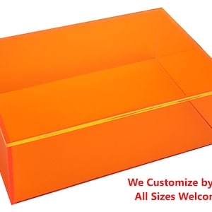 May include: A bright orange acrylic box with a gold trim. The box is empty and has a rectangular shape. The text "We Customize by size! All Sizes Welcome!!" is printed below the box.