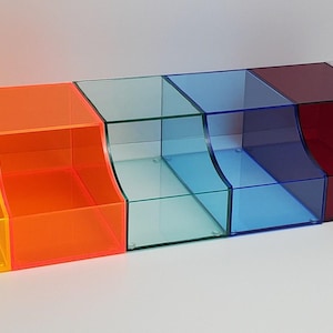May include: Set of 8 acrylic storage boxes with curved fronts. The boxes are in various colors, including yellow, orange, light blue, dark blue, red, white, and black.