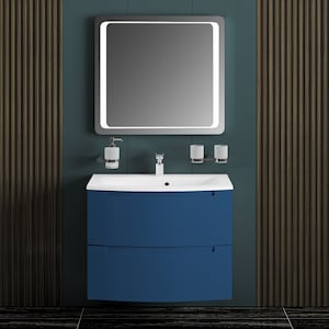 Puede incluir: Un tocador de ba&ntilde;o azul con dos cajones y un lavabo de porcelana blanca. El tocador tiene un frente curvo y est&aacute; montado en la pared. Un espejo con una luz alrededor del per&iacute;metro est&aacute; montado sobre el tocador.