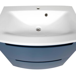 Puede incluir: Un lavabo de cer&aacute;mica blanco con un gabinete azul con dos cajones. El lavabo est&aacute; montado en la parte superior del gabinete.