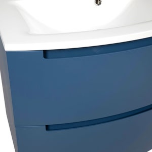 Puede incluir: Un mueble de ba&ntilde;o azul con dos cajones y un lavabo de cer&aacute;mica blanca. El mueble tiene un frente curvo y tiradores empotrados.