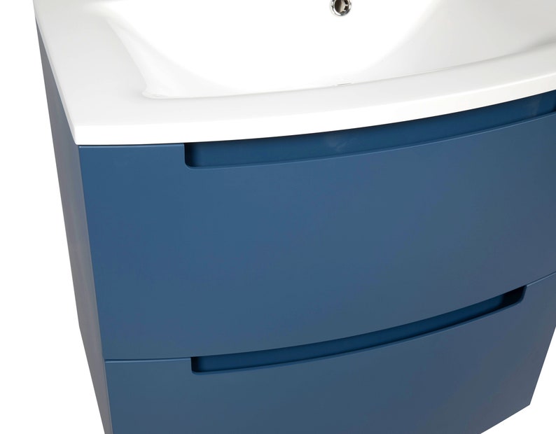 Puede incluir: Un mueble de ba&ntilde;o azul con dos cajones y un lavabo de cer&aacute;mica blanca. El mueble tiene un frente curvo y tiradores empotrados.