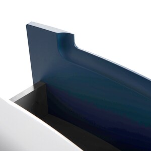 Puede incluir: Primer plano de una unidad de almacenamiento azul y blanca con un dise&ntilde;o curvo. La unidad tiene un caj&oacute;n que est&aacute; parcialmente abierto, revelando un interior negro.