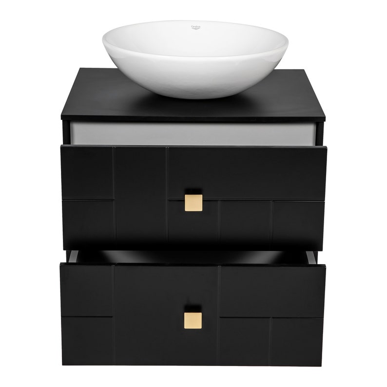 May include: Black bathroom vanity with two drawers and a white ceramic vessel sink. The drawers have gold square handles and a geometric pattern.