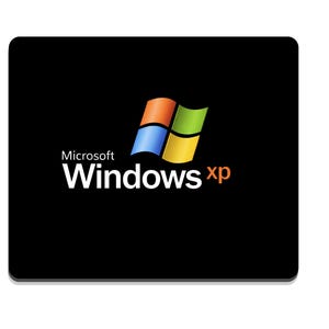 May include: A rectangular black mouse pad featuring the Microsoft Windows XP logo in the center. The logo consists of a four-colored flag graphic in blue, red, green, and yellow, with the white text Microsoft Windows and the orange text xp.