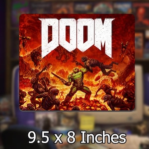 May include: A rectangular mouse pad measuring 9.5 by 8 inches featuring the DOOM logo in white text at the top. The graphic depicts a green-armored character holding a shotgun in a fiery, hellish landscape filled with various dark creatures.