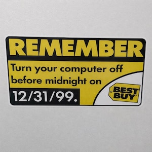 May include: A rectangular sticker with a yellow and black design. The text reads "REMEMBER" at the top, followed by "Turn your computer off before midnight on 12/31/99." The Best Buy logo is in the bottom right corner.