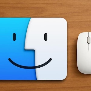 May include: A rectangular mouse pad featuring a blue and white graphic of a smiling face icon with two black oval eyes and a curved black mouth. Beside the mouse pad is a white computer mouse with a central scroll wheel and two buttons.