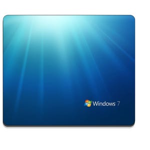 May include: A rectangular mouse pad featuring the Windows 7 operating system logo and branding. The surface displays a deep blue gradient background with light rays emanating from the top left corner toward the bottom right corner.