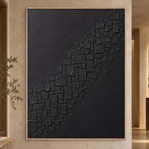 Può includere: Una grande opera d'arte murale rettangolare caratterizzata da una superficie nera solida con una fascia diagonale di forme quadrate e rettangolari in rilievo e testurizzate. L'opera è racchiusa in una sottile cornice di legno di colore chiaro.