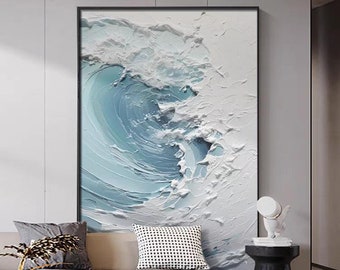 Könnte beinhalten: Ein gerahmtes abstraktes Gemälde einer blauen und weißen Welle. Das Gemälde hängt an einer weißen Wand in einem Wohnzimmer.