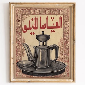 May include: Framed vintage-style print featuring a black and grey teapot with a small saucer. The print has a beige background with red Arabic text and decorative borders, within a gold-coloured frame.