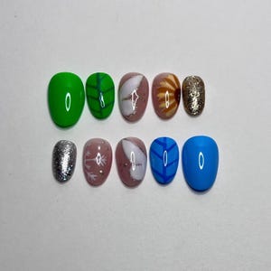May include: A set of ten press-on nails featuring a variety of designs including solid bright green and blue, green and blue leaf patterns, white butterfly wings on a mauve base, a sunflower motif, and silver and gold glitter accents.