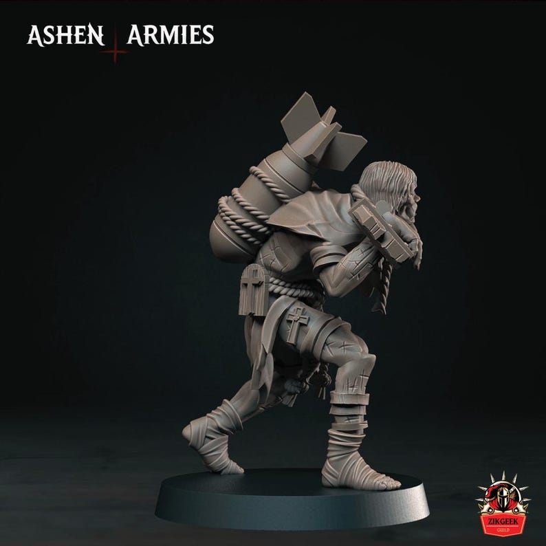 May include: A grey miniature figurine of a hunched figure carrying a large bomb on their back, secured with rope. The figure wears tattered clothing with cross symbols and wraps around their legs. The text ASHEN ARMIES appears at the top left.
