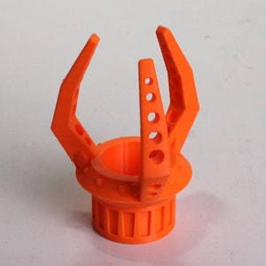 May include: Orange 3D printed plastic claw with a round base and a series of holes around the top of the base.