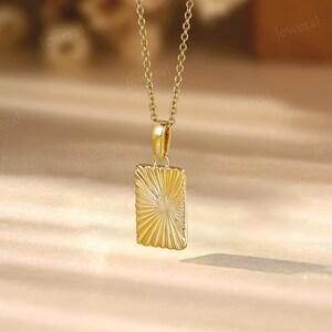 a gold necklace with a square pendant on a table