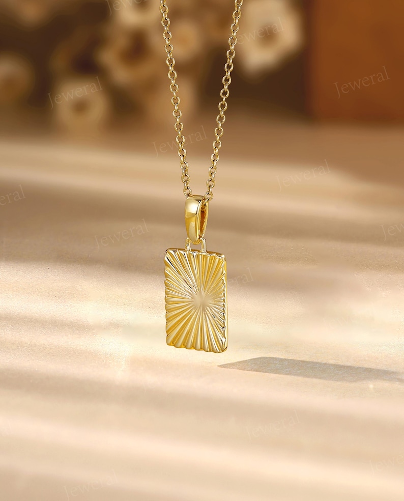 a gold necklace with a square pendant on a table