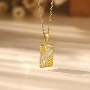 a gold necklace with a square pendant on a table
