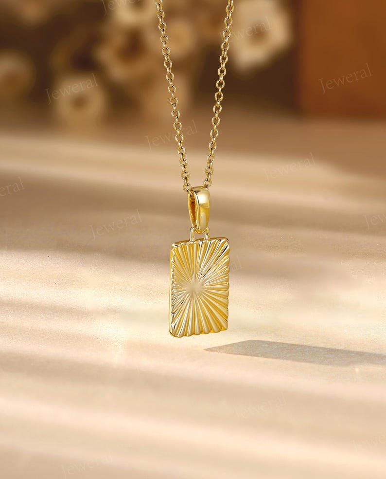 a gold necklace with a square pendant on a table
