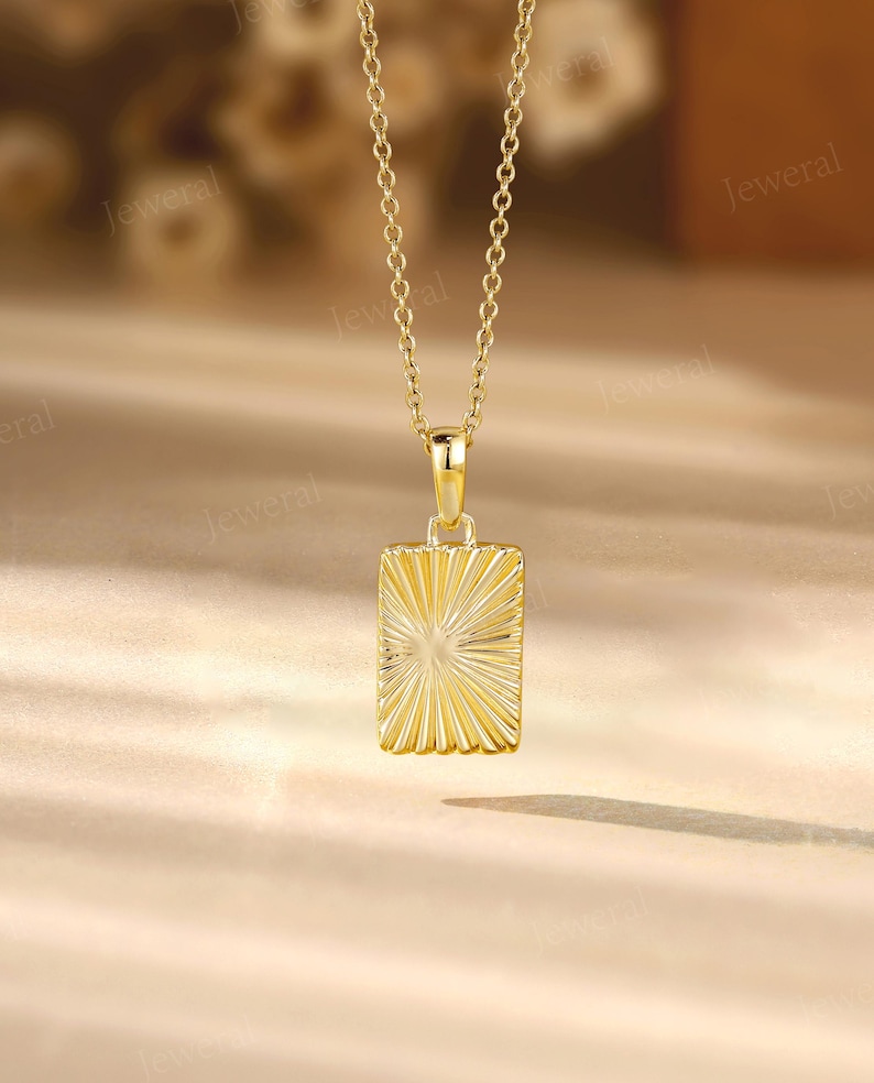 a gold necklace with a square pendant on a table