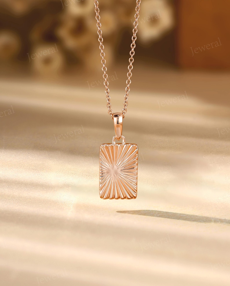 a gold necklace with a square shaped pendant