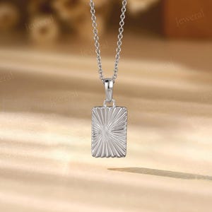 a silver square pendant on a silver chain