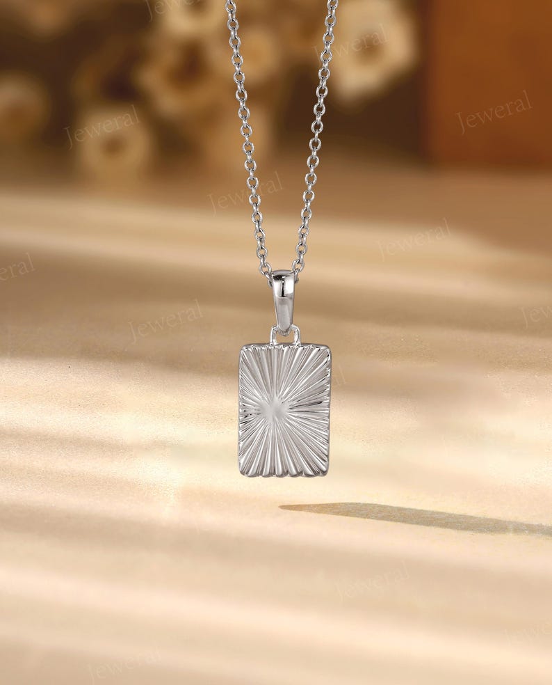 a silver square pendant on a silver chain