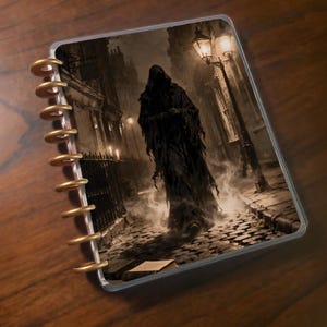 May include: A spiral-bound notebook with a cover featuring a sepia-toned illustration of a cloaked figure in a foggy cobblestone street. The figure stands near a lit gas lamp, with a book on the ground. The notebook has gold-colored rings.