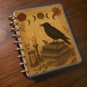 May include: A spiral-bound journal with a vintage-style cover featuring a black crow perched on books. The cover art includes a candle, hourglass, and phases of the moon in sepia tones. The journal has gold-colored rings.