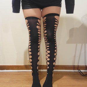 May include: Black fishnet stockings with a cut-out design. The stockings are worn on a person's legs.