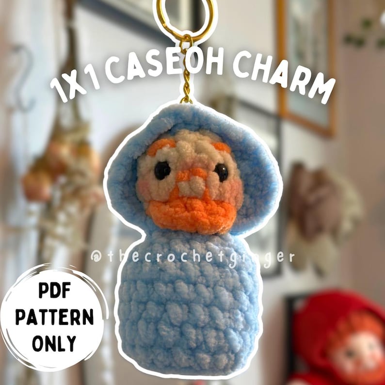 May include: A handmade crochet duck charm with a blue hooded outfit and orange beak. The charm is attached to a gold keychain. Text on the image reads "1x1 Caseoh Charm" and "PDF Pattern Only".