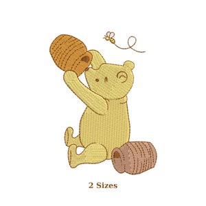 May include: Embroidered image of a yellow bear holding a honey pot, with a bee flying nearby. The bear is sitting with a second honey pot on the ground. The text "2 Sizes" is below the image.