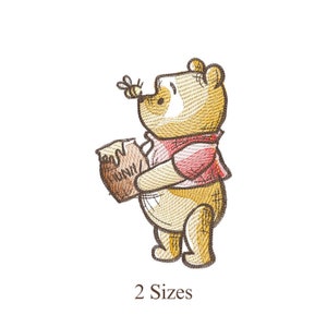 Puede incluir: Imagen bordada de un oso amarillo con una bufanda roja, sosteniendo un tarro de miel y con una abeja cerca de su nariz. El texto "HONEY" es visible en el tarro de miel. El texto "2 Sizes" está debajo.