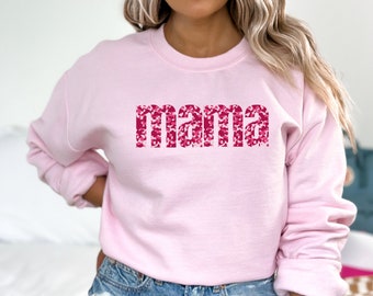 May include: Pink sweatshirt with the word "mama" printed in pink and white camouflage pattern.