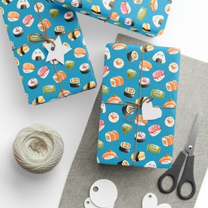 May include: Three gift boxes wrapped in blue wrapping paper with a sushi pattern. The pattern includes various sushi rolls, nigiri, and other Japanese food items. The boxes are tied with twine and have white paper tags attached.
