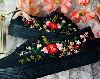May include: Black canvas low-top sneakers with colorful floral embroidery. The embroidery features pink, red, and green flowers.