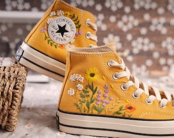 May include: Yellow high-top Converse sneakers with embroidered flowers and the text "Converse All Star" on the side.
