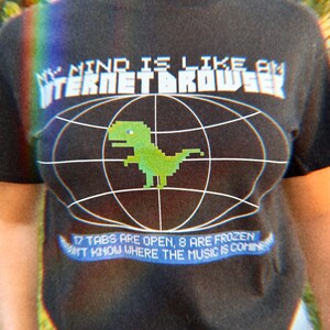 Könnte beinhalten: Schwarzes T-Shirt mit einer weißen Grafik eines Dinosauriers in einem Kreis mit dem Text "My mind is like an internet browser" und "17 tabs are open, 8 are frozen. Don't know where the music is coming from."
